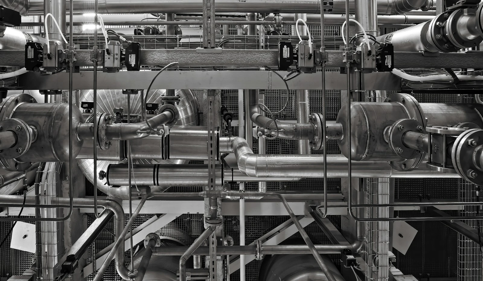 Réseau de tuyauteries métalliques et de vannes dans un environnement industriel en Suisse.